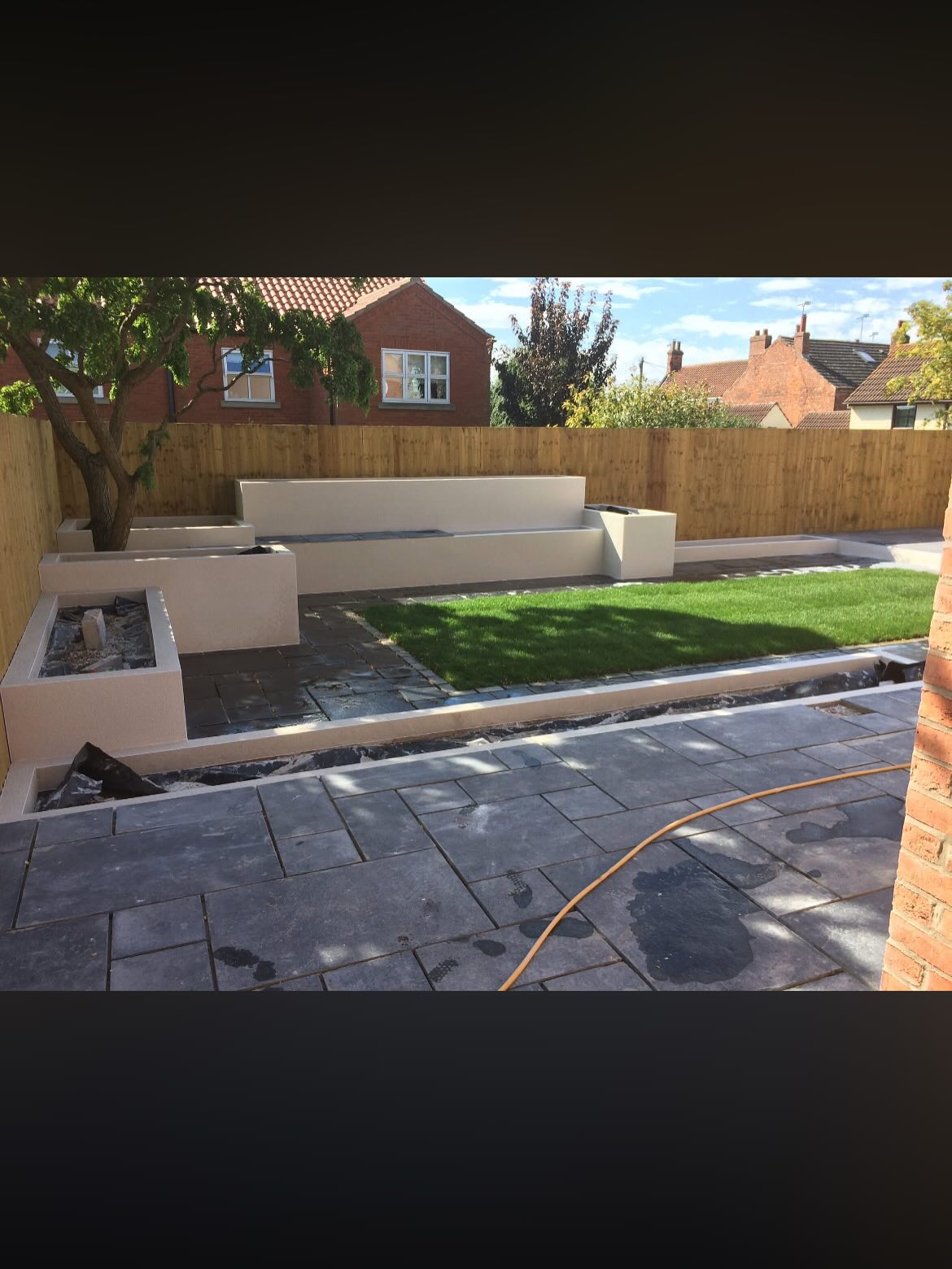 Bespoke rendered garden planters and seating wall with porcelain paving