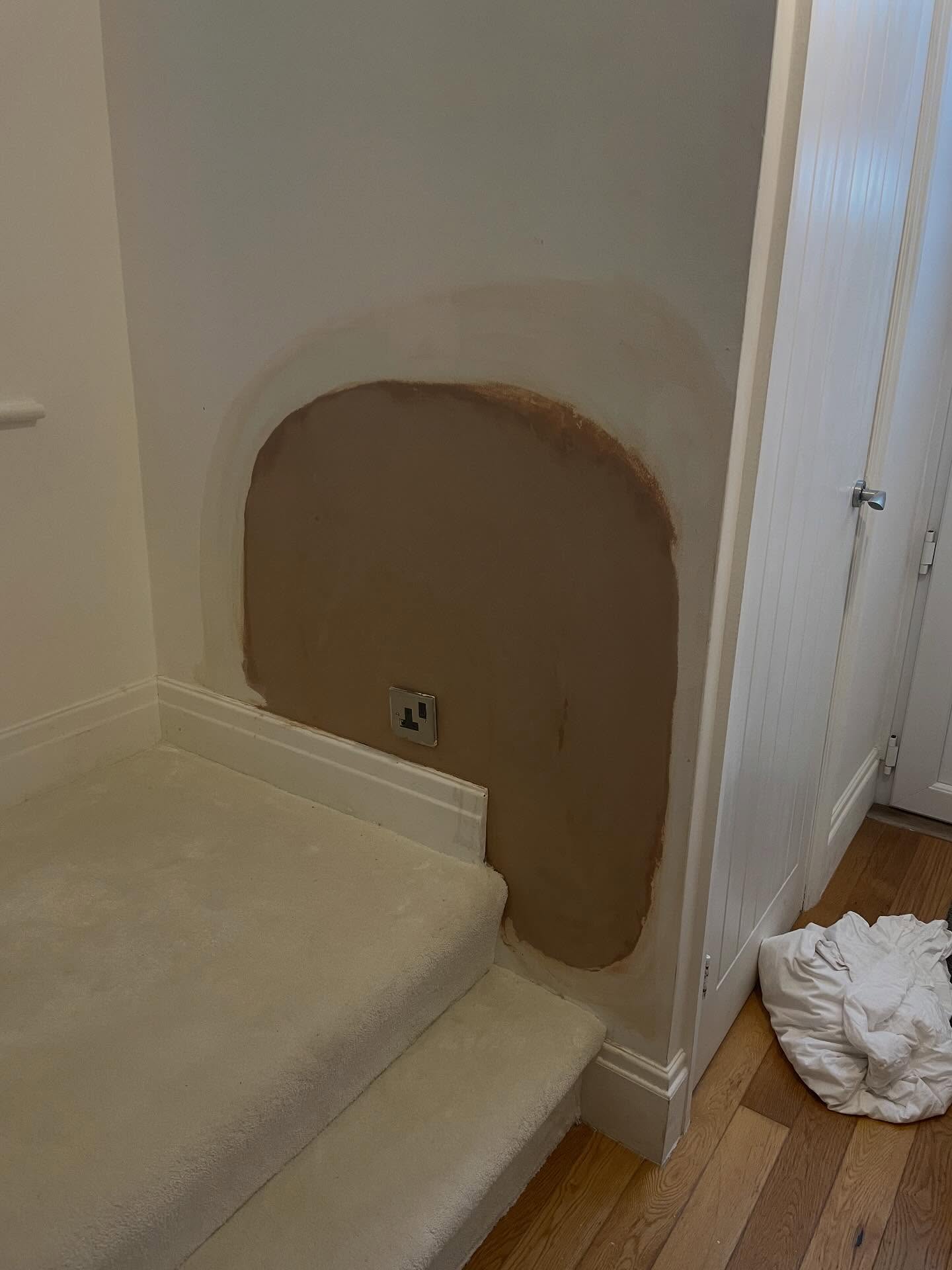 Neat patch repair on a stair-landing wall, blended into the existing finish